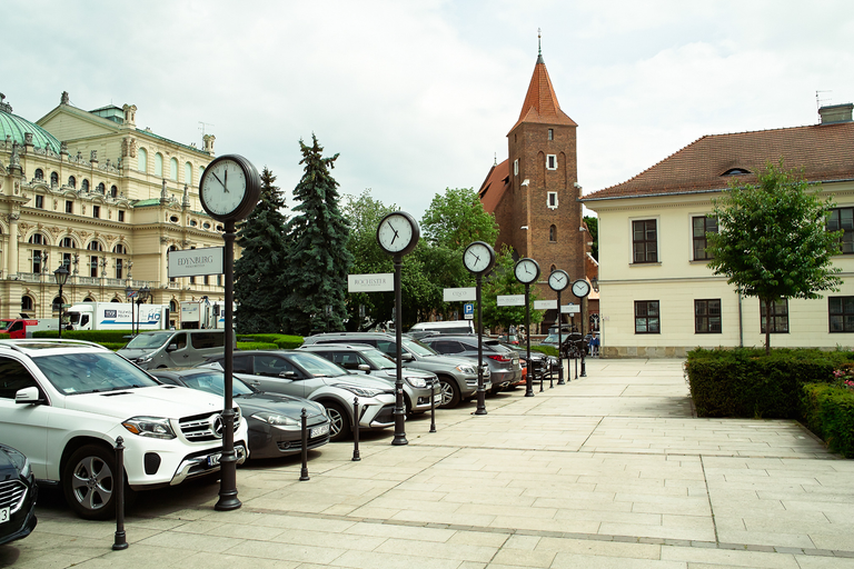 Plac z zegarami miast partnerskich Krakowa przy Teatrze im. Słowackiego, widok z zaparkowanymi samochodami
