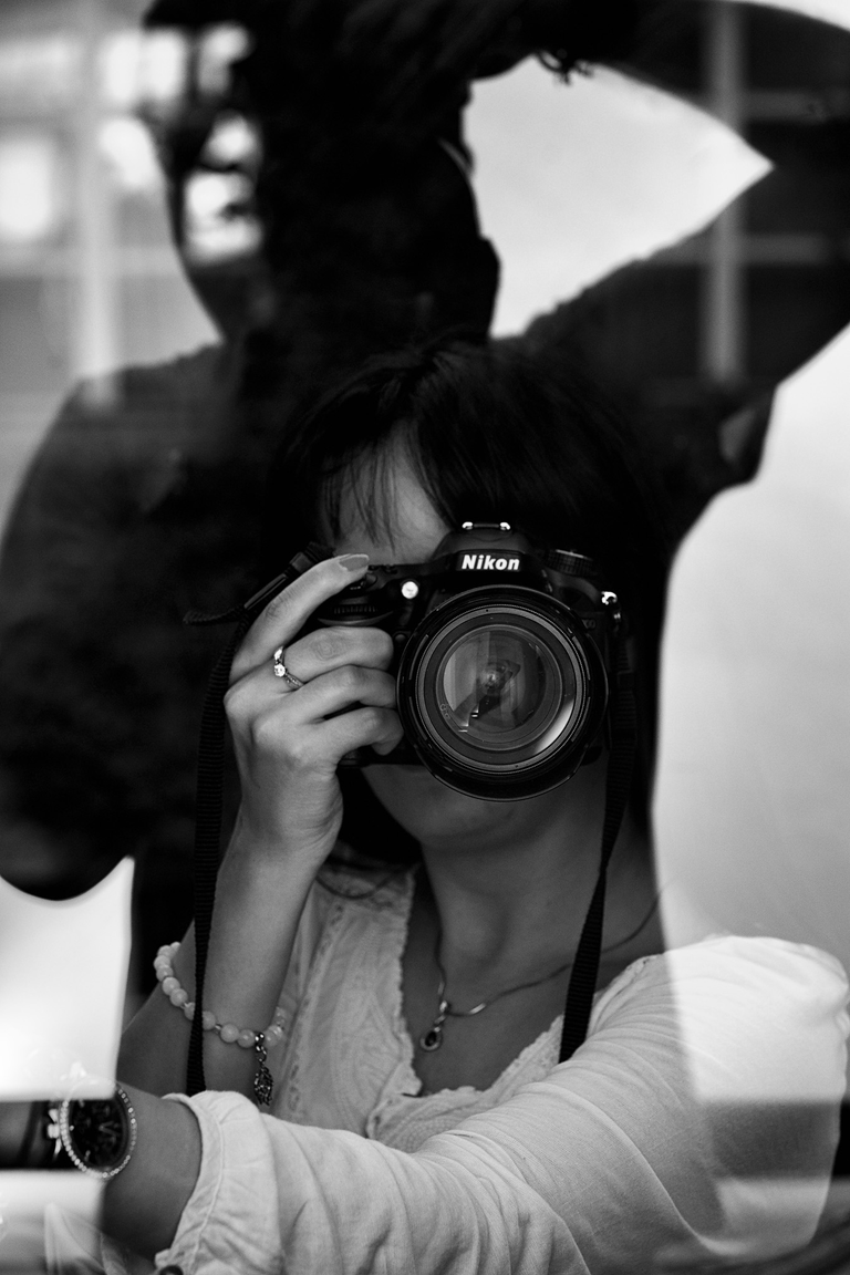 Konceptualna fotografia portretowa. Magda pozuje z aparatem fotograficznym. Portretowa sesja zdjęciowa w czerni i bieli.