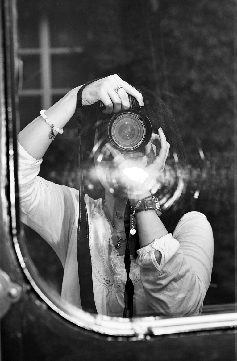 Konceptualna fotografia portretowa. Magda trzyma w rękach aparat fotograficzny. Portretowa sesja zdjęciowa w czerni i bieli.