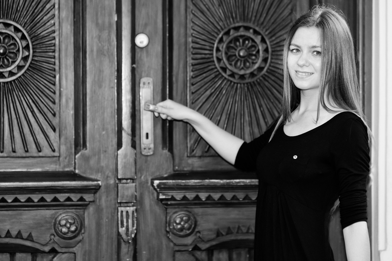 Portretowa sesja zdjęciowa w czerni i bieli. Angelika otwiera drzwi Pałacyku Henryka Sienkiewicza w Oblęgorku.