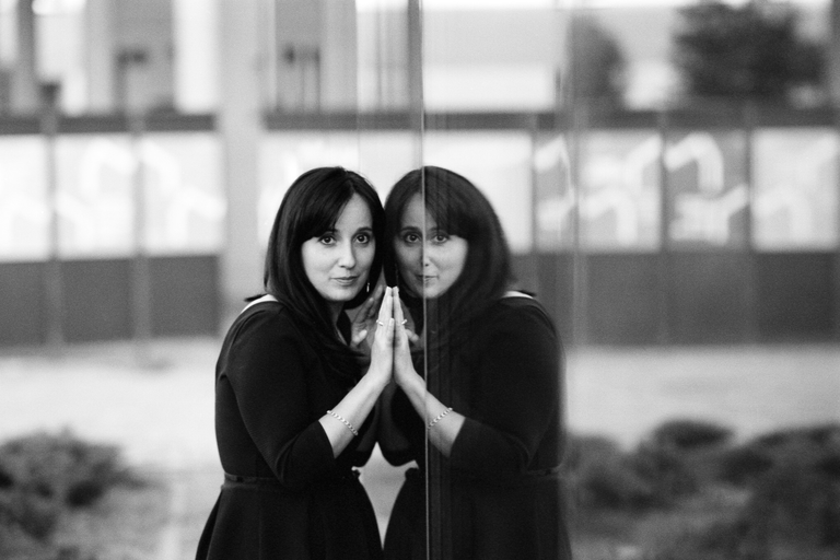 Konceptualny portret uliczny przedstawiający odbicie postaci modelki w szybie. Portretowa sesja zdjęciowa w czerni i bieli.