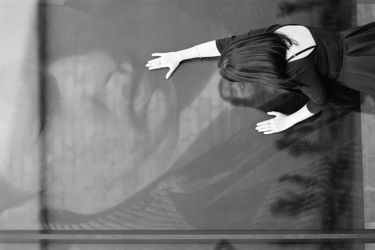 Konceptualny portret uliczny. Modelka dotyka ust mężczyzny na plakacie za szybą. Portretowa sesja zdjęciowa w czerni i bieli.