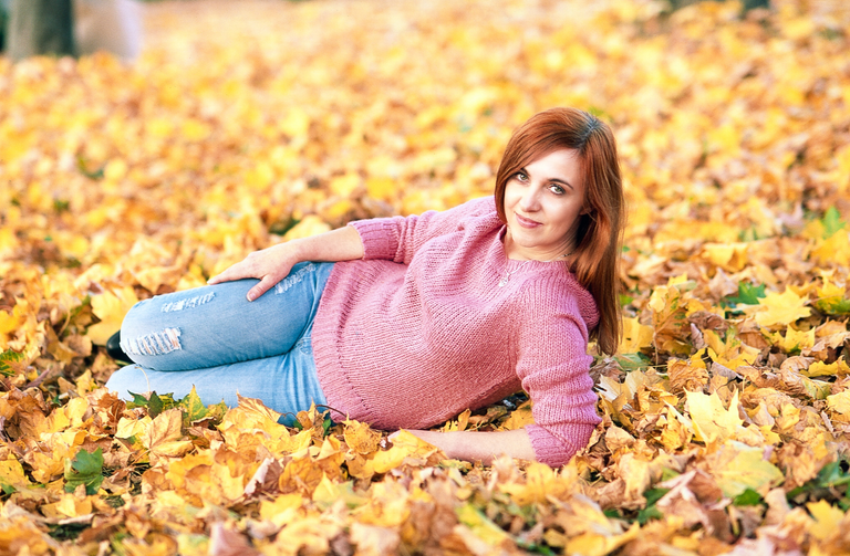 Portretowa sesja zdjęciowa Moniki w ciepłe, słoneczne, październikowe popołudnie. Monika leży w złocistych liściach.