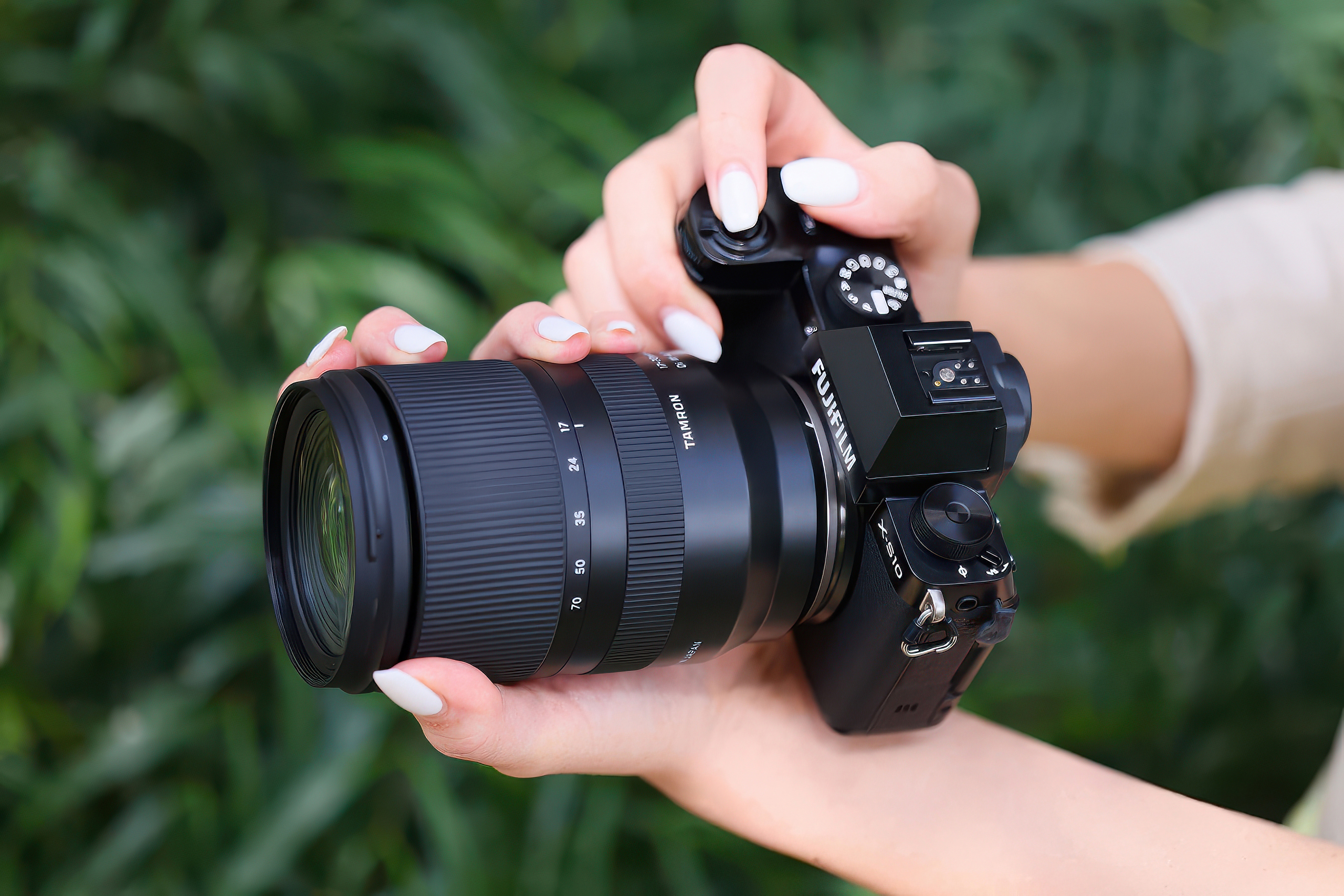 Kobiece dłonie trzymają aparat Fujifilm X z obiektywem Tamron 17–70mm F/2.8 Di III-A VC RXD